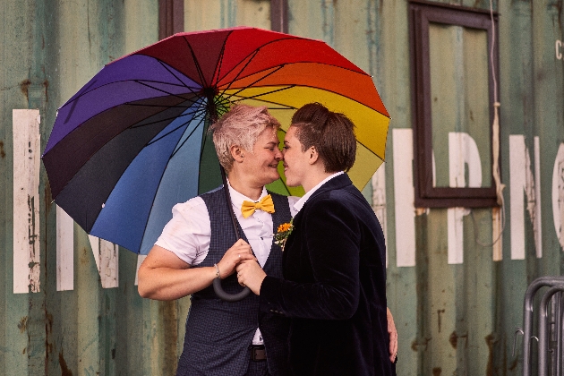Couple standing under umbrella outside wedding venue Victoria Warehouse
