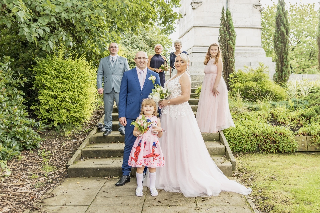 Bride and groom standing with their bridal party on the steps of their wedding venue