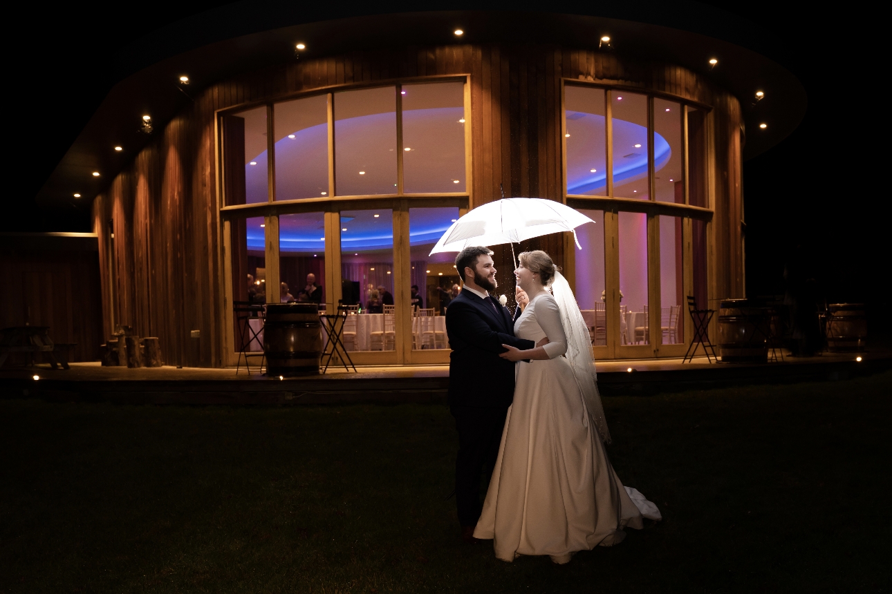 Couple stand under illuminated umbrella