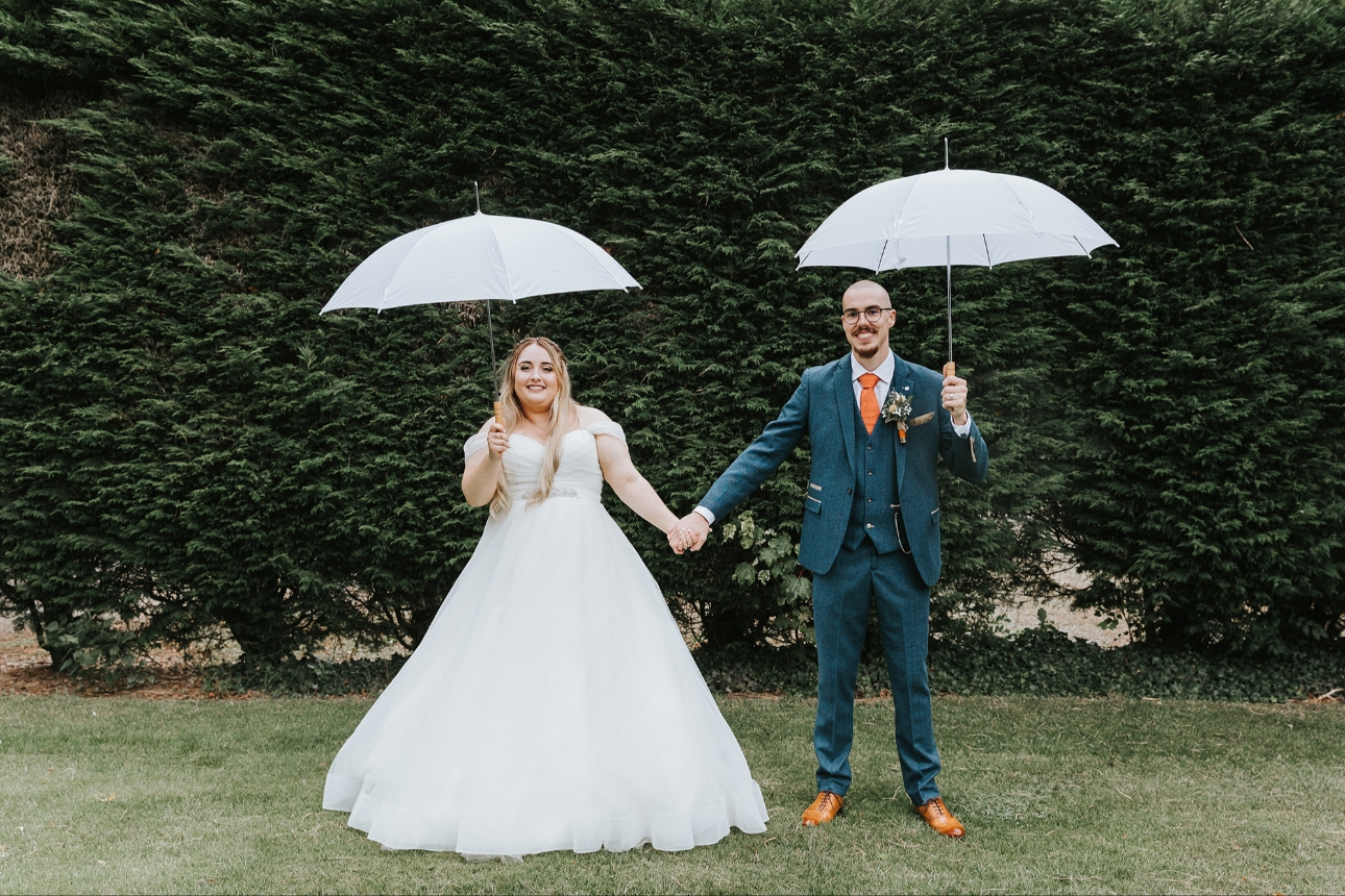 Bride and groom pose with umbrellas up