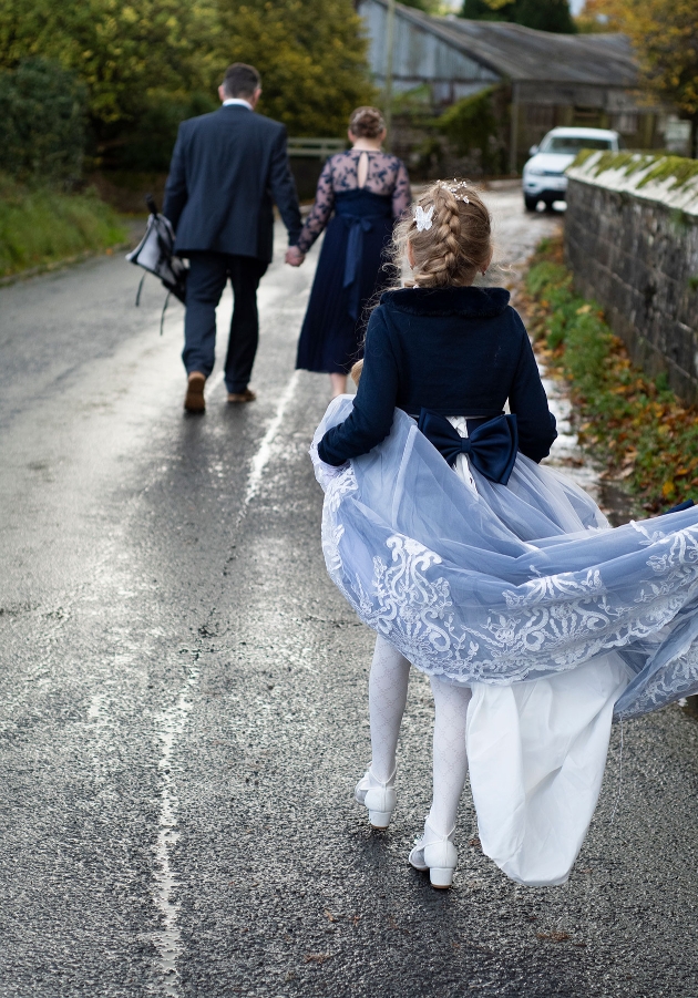 Bride, groom and daughter walking down lane