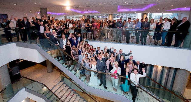 A wedding party waving on the stairs of The Lowry Hotel