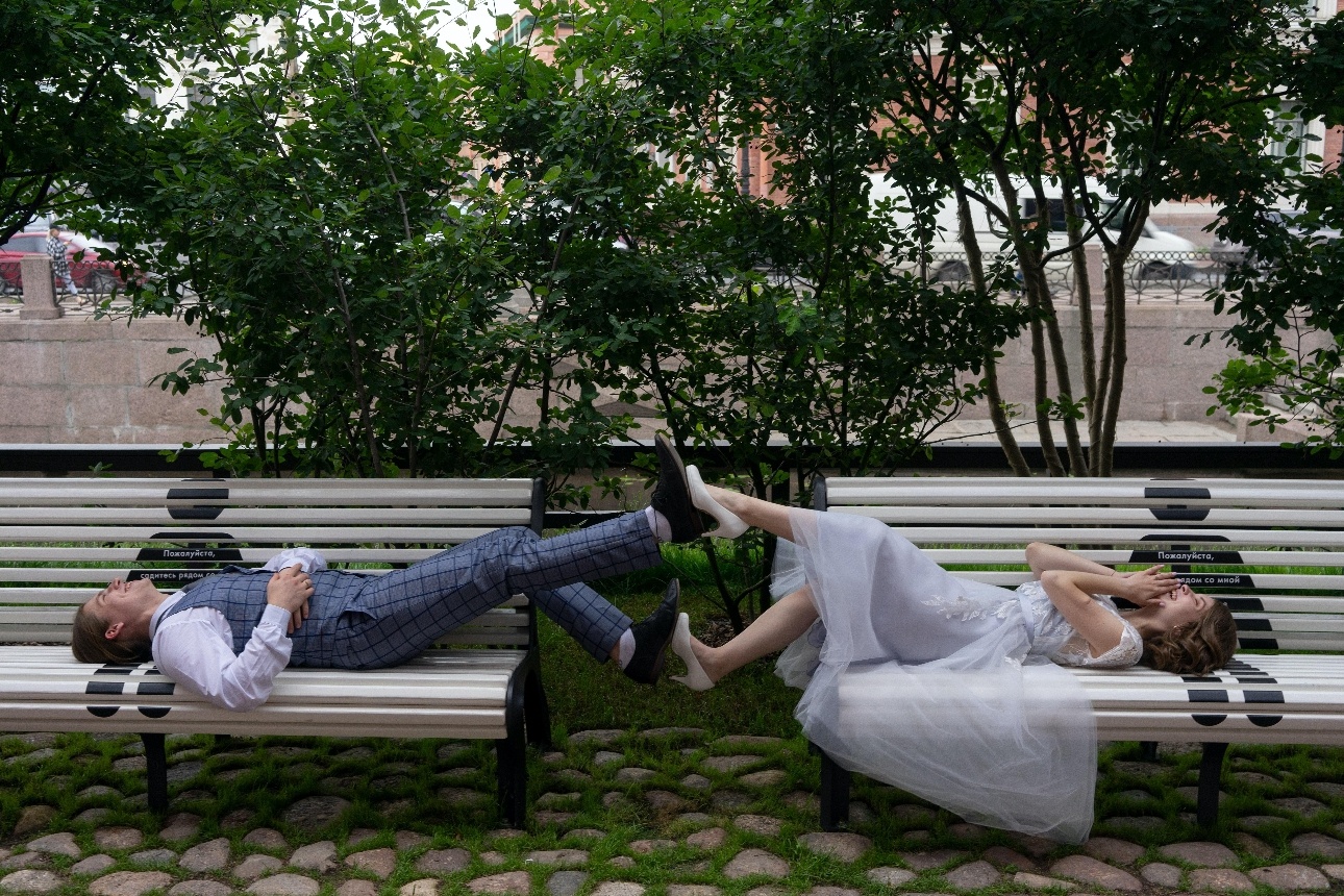 bride and groom laying on benches outside touching feet in the middle