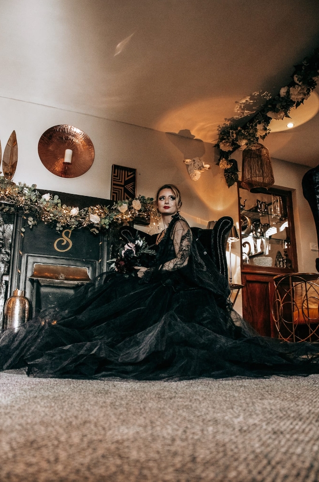 Bride sitting in a chair in a black wedding dress