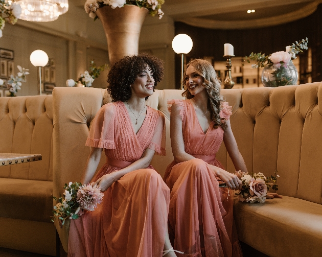 Two bridesmaids sitting on a sofa laughing