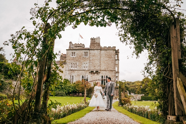 Bride and groom walking hand-in-hand outside Leighton Hall