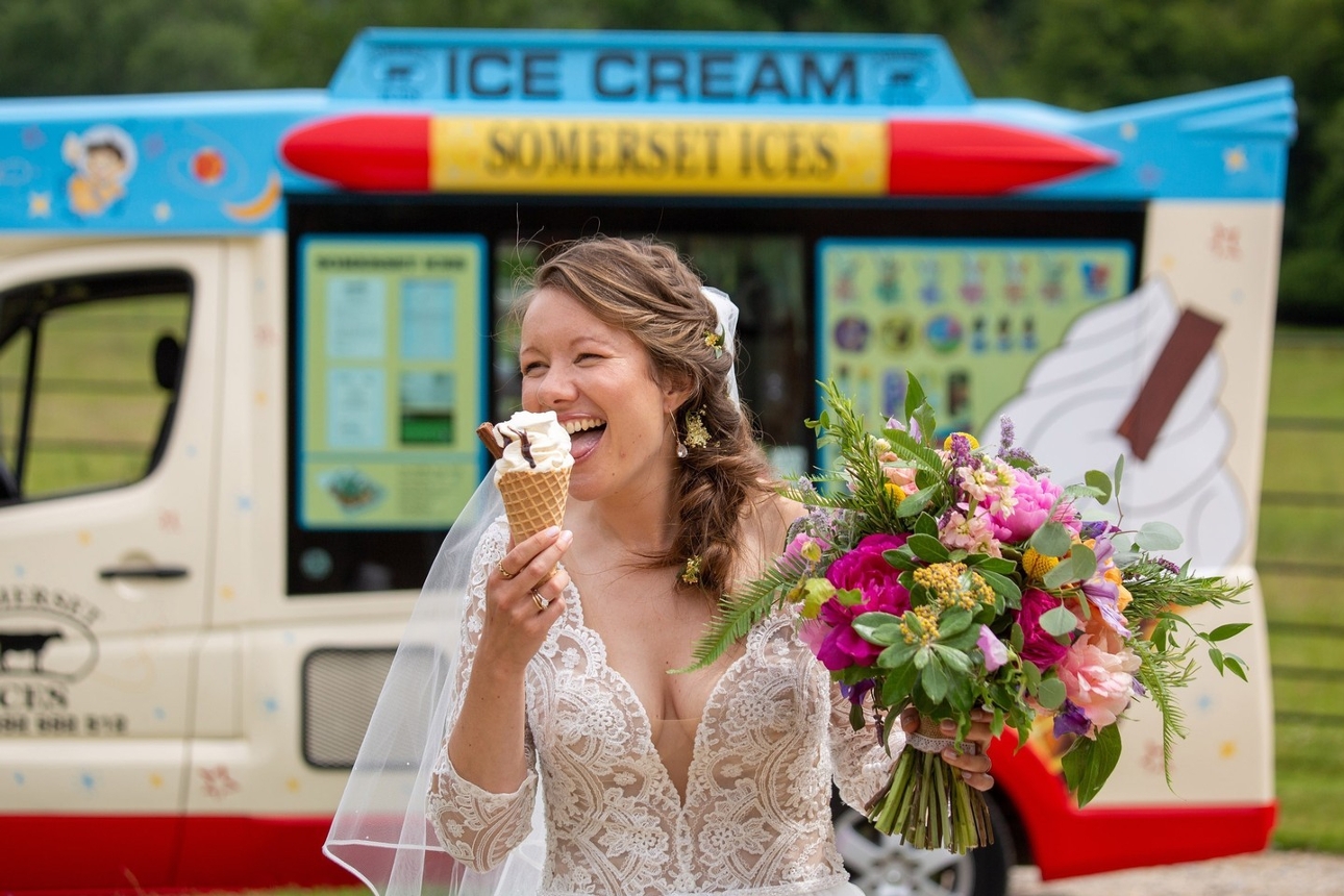 bride in dress licking an icecream with an icecream van in background