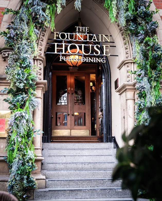 A grand archway with a sign for The Fountain House hanging in front of the arch