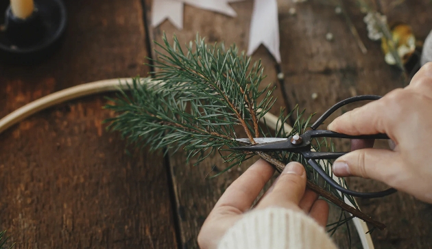 A person cutting a twig to be used on a wreath