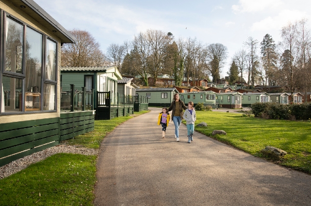 A woman walking with two children outside a row of green holiday homes