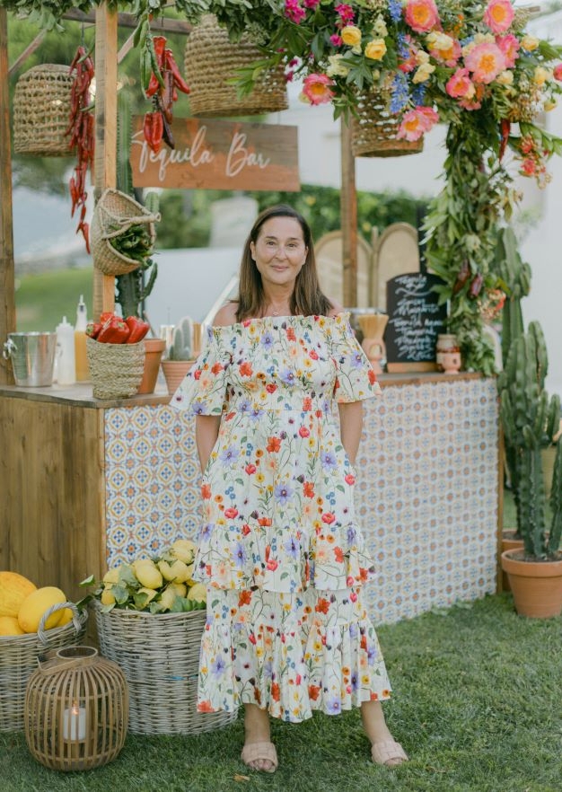 emma at a wedding with creative bar scene behind her