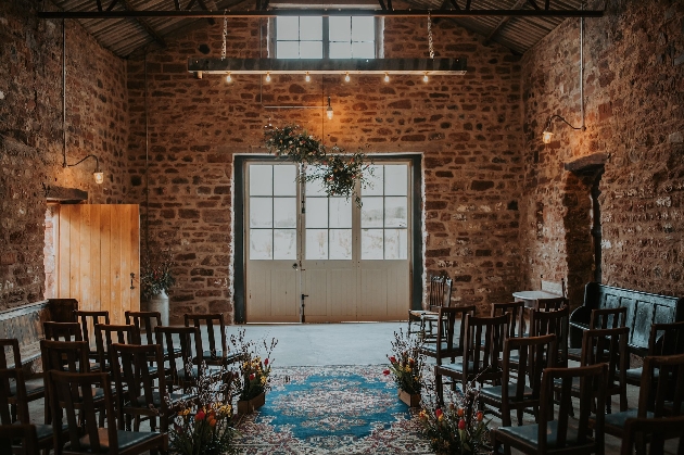 A barn with brick walls and chairs lining an aisle