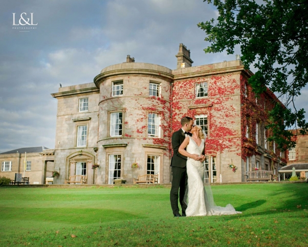 A bride and groom kissing in front of a grand stone building