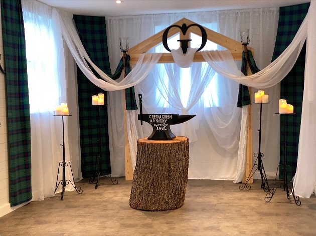 A small room with an anvil in the middle and drapes hanging from the windows