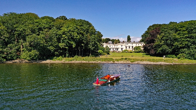 A boat sailing towards a large white building