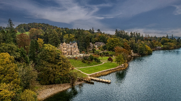 A large manor house nestled in acres of woodland next to a lake