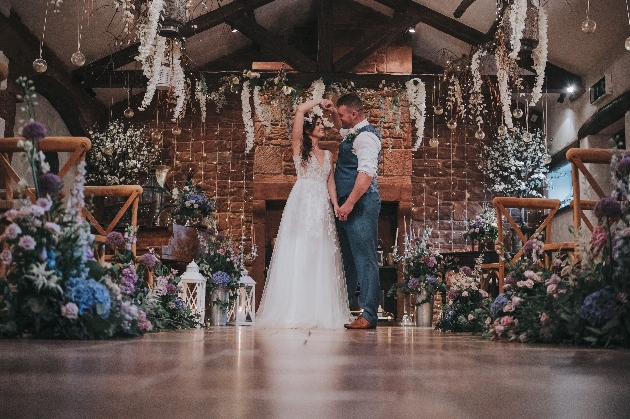 A bride and groom dancing in a barn decorated with flowers and candles
