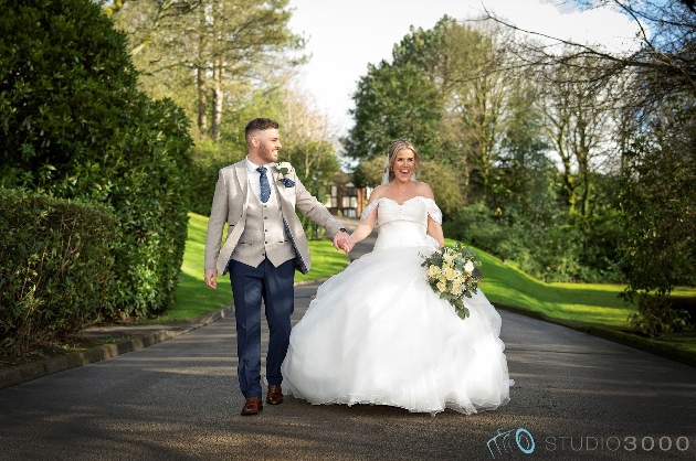 A bride and groom laughing while walking hand-in-hand
