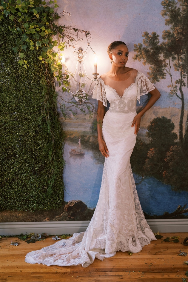 woman standing in front of a botanical background in lacey dress