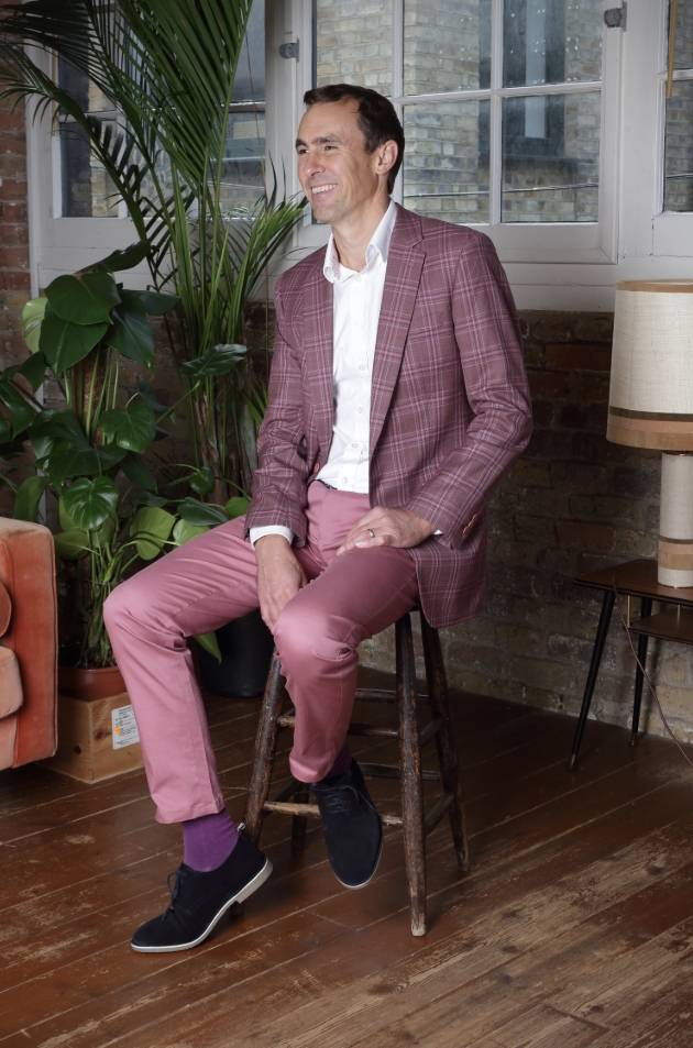 man in pink toned suit sat on chair