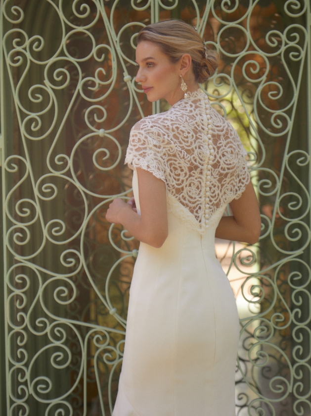 woman in high-neck dress posing in front of a gate