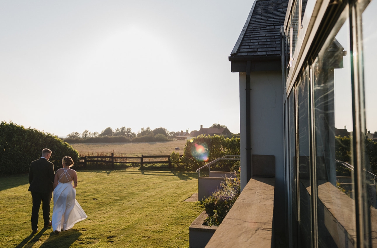 bride and groom walking in garden at sunset