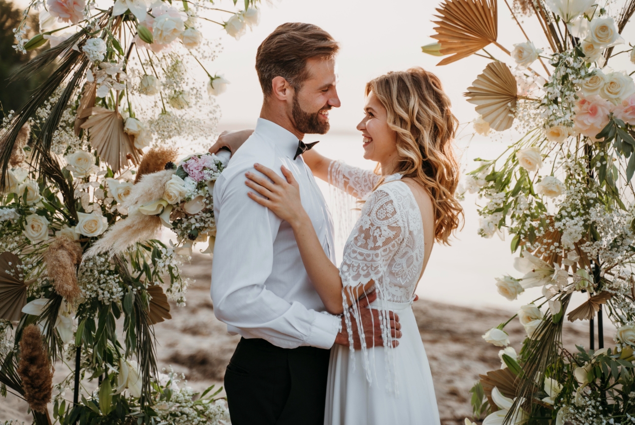 wedding couple under floral arch getting married