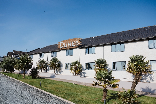 The exterior of a large white building with a sign above it saying Dunes