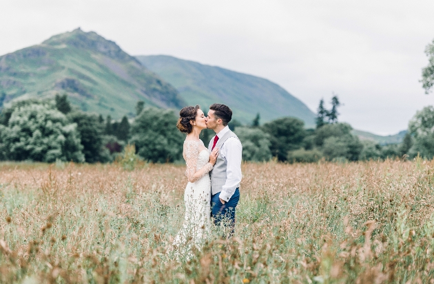 A bride and groom standing in front of a hill