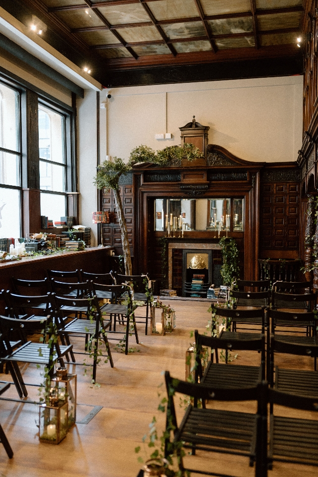 A ceremony set up inside a library with a fireplace at the end of the aisle