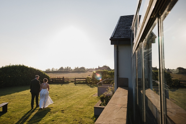 A bride and groom walking in the gardens of a venue