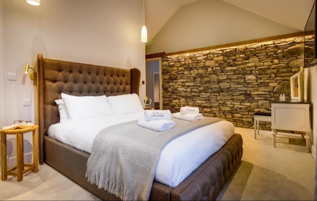 A picture of a large bed with a brown headboard