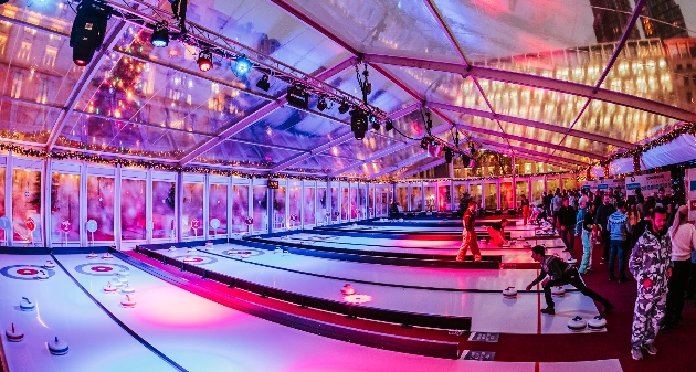 A large glass room with people playing curling in it