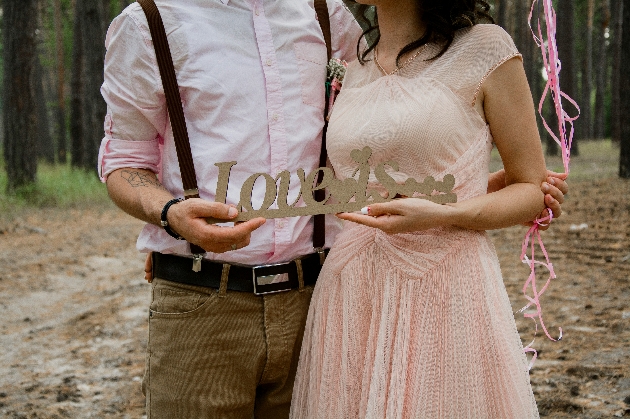A bride and groom holding a sign that says Love