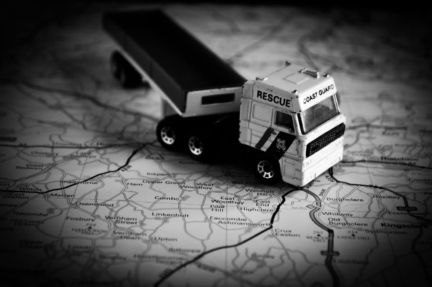 A black and white image of a toy truck on a map of the UK
