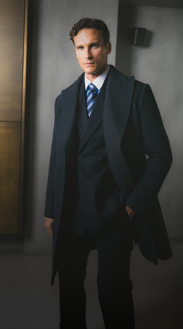 A man wearing a suit and black long coat